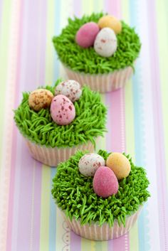 three cupcakes decorated with grass and eggs