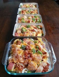 four plastic containers filled with food on top of a wooden table