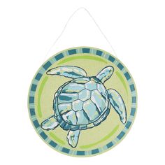 a green and blue turtle hanging on a white wall or door hanger with an image of a sea turtle painted on it's side