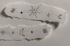 two torn pieces of paper with drawings on them, one has the sun and moon