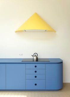 a blue cabinet with drawers and a yellow light above it in a white walled room