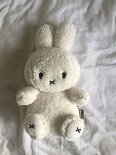 a white stuffed animal sitting on top of a bed