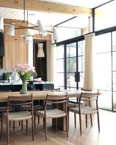 a dining room table and chairs in front of large windows