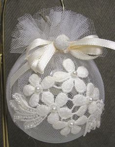 a white ornament hanging from a wire with flowers and leaves on it's side