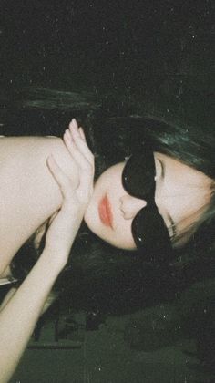 a woman with sunglasses on her head is laying down in the dark and has her eyes closed