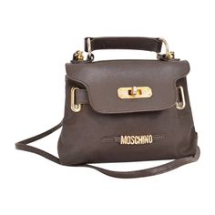 A Chic and Fun Vintage 1990's Moschino brown nylon miniature 'Kelly' bag with gold tone metal hardware and leather features. Features: Detacheable shoulder strap Belt loop option Top handle MOSCHINO Gold Tone Metal lettering Made In Italy Measurements: 2'' Width x 5'' Depth x 7'' Length Strap: 48'' Condition: 7/10 Some tarnishing to the hardware and signs of general usage. Moschino Vintage, Metal Lettering, Micro Bag, Kelly Bag, Metal Letters, 80s Fashion, Vintage Jewellery, Metal Hardware, All Pins