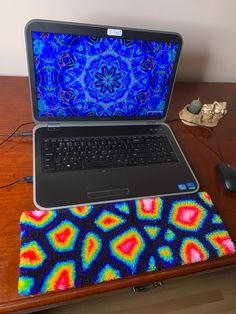 an open laptop computer sitting on top of a wooden desk next to a mouse pad