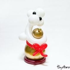 a gold and white bear figurine with a red ribbon around its neck