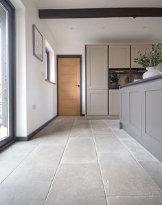 an empty kitchen with tile flooring next to a door and window in front of it