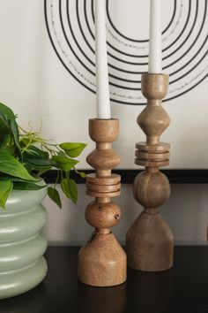 three wooden candlesticks sitting on top of a table next to a potted plant