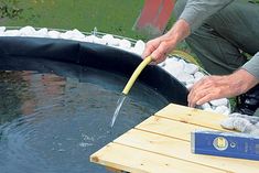 a man is using a large knife to cut rocks into the water in an outdoor pond