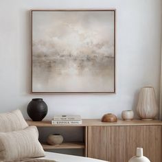 a painting hanging on the wall above a bed in a room with white walls and wooden furniture