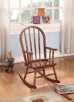 a wooden rocking chair sitting on top of a hard wood floor next to a window