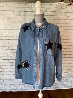 This upcycled light blue denim shacket is a one-of-a-kind design embellished with black stars hand sewn on the front and back. It also has rhinestones sewn around one star and on the point of one side of the collar. This distressed and trendy shirt jacket would look great with black leggings. Jacket (or coat) is an XL, approximately women's size 14-16. Measures 18" across the shoulders, 31" top of collar to bottom and sleeves are 24" long.  One of our favorites! Find more embellished jackets at our Etsy store, ClarettasCreations. Embellished Jackets, Denim Shacket, Denim Shirt Jacket, Black Stars, Embellished Jacket, Trendy Shirts, One Star, Light Blue Denim, Black Star