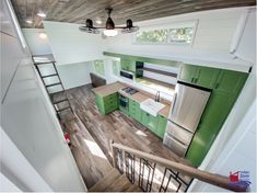 a kitchen with green cabinets and stairs leading up to the upper floor, along with white walls