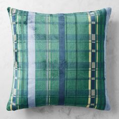 a green plaid pillow sitting on top of a white wall