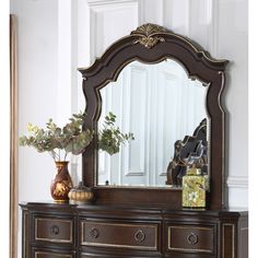 an ornate dresser with mirror and vase on top