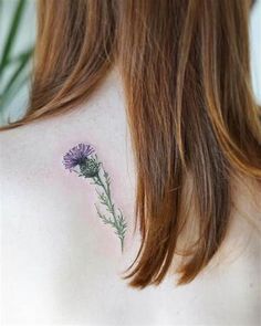 the back of a woman's shoulder with a flower tattoo on it