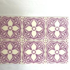 four purple and white tiles with flower designs on the sides, all in different shapes