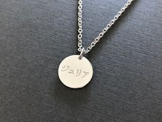 This is for a personalized engraved Japanese name necklace of your choice from the metal: gold plated brass or gold plated sterling silver. The sterling silver base jewelry is nickel free. The white gold plated sample necklace is engraved with a name Julia in Japanese in the font #2. One side or both sides, front & back can be engraved in Japanese and numbers. Please check the font options in the pictures. The sample pendant is 1.5 cm (0.6 inches) wide. The available 2 pendant sizes are 1.5 cm ( Silver Round Pendant Name Necklace, Customizable Silver Necklace With Round Pendant, Silver Custom Necklace With Round Pendant, Silver Necklaces With Engraved Text For Personalized Gift, Silver Custom Name Necklace With Round Pendant, Custom Silver Necklace With Name On Round Pendant, Silver Custom Necklace With Name On Round Pendant, Personalized Silver Necklace With Engraved Text, Personalized Silver Necklace With Round Pendant