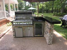 an outdoor kitchen with grill, sink and umbrella