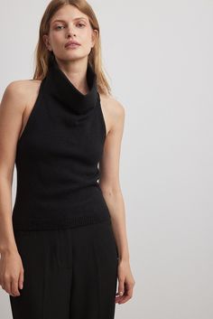 This top is knitted and elasticized and features a halterneck with a high neckline. Luxury Halter Neck Top For Workwear, Luxury Fitted High Neck Halter Top, Luxury Evening Halter Neck Top, Luxury Knit High Neck Top, Luxury Black Knit Top For Night Out, Luxury High Neck Halter Top In Chic Style, Luxury Halter Neck Top For Evening, Luxury Fine Knit High Neck Tops, Luxury High-neck Fine Knit Top