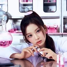 a young woman is sitting at a table in front of some pink flasks