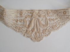 This beautiful, hand made piece of cream colored lace is quite versatile and can be used as a high neck collar to incorporate into a bridal dress. It also looks fabulous as an Art Deco head piece. It fits perfectly on the forehead. This wonderful French antique lace has a long scallop  edged length of lace to hold it in place. One side has a length of 6.5 inches on a side of the central V shaped piece and 26 inches on the other side of the V. The two pieces are not joined and can easily be stitched together or a piece can be cut off so the piece can be used as a head piece or as a high neck collar. It is a unique item that is in excellent condition .  It has a total width of 41.5 inches. The V shaped piece is 9 inches wide x 4 inches high. Elegant Cream Lace With Patchwork, Elegant Beige Scalloped Lace, Victorian Cream Lace For Vintage Events, Cream Fitted Delicate Lace, Delicate Fitted Cream Lace, Fitted Delicate Cream Lace, Vintage Cream Lace For Ceremonies, Vintage Cream Lace For Ceremony, Elegant Beige Lace With Lace Trim