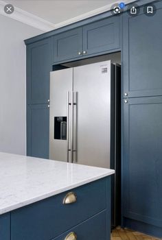 a stainless steel refrigerator in a kitchen with blue cabinets