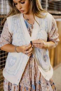 Introducing The Rachel Vest - a playful spring and summer layering piece with a blue embroidered detail. This collarless, button-up sweater vest top comes in a cream/blue color that will add a touch of quirkiness to any outfit. Haylee is wearing size small paired with The Jane Dress Spring Cotton Sweater Vest, Spring Cotton Vest For Layering, Cotton Vest For Spring Layering, Cotton Vest For Layering In Spring, Chic Cream Sweater Vest For Spring, Blue Cotton Vest For Spring, Fitted Sweater Vest For Spring Layering, Fitted Cotton Sweater Vest For Spring, Fitted Sweater Vest For Spring Day Out