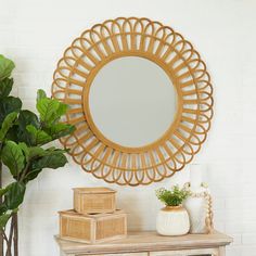 a round mirror sitting on top of a wooden dresser next to a potted plant