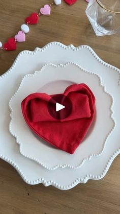 a white plate topped with a red heart on top of a wooden table