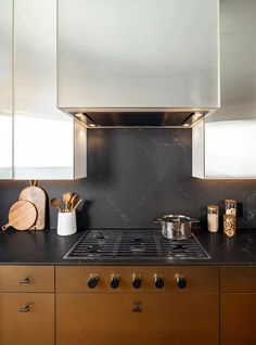 a stove top oven sitting inside of a kitchen next to a counter with utensils on it