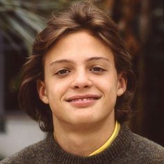 a close up of a person wearing a turtle neck sweater and smiling at the camera