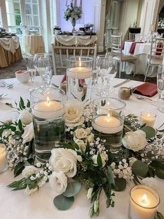 a table topped with lots of white flowers and candles