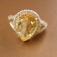 This is a beautiful multi faceted pear shaped large citrine gemstone with many faux diamonds bordering the main center piece. A great engagement/ cocktail ring. Crafted in sterling silver, size 5 3/4. Called The Merchant's Stone for its properties of increase in the cashbox, sparkling yellow Citrine not only assists in acquiring wealth, but helps in maintaining it. Carrying a Citrine attracts love and happiness, and guards against those who would break your heart. 11-3 2014 8-1-20 oct1 2020 Pear-shaped Jewelry With Gemstone Accents, Pear-shaped Gemstone Wedding Jewelry, Pear-shaped Gemstone Accents Jewelry For Anniversary, Pear-shaped Gemstone Accented Jewelry For Anniversary, Pear-shaped Gemstone Jewelry For Anniversary, Pear-shaped Gemstone Anniversary Jewelry, Wedding Jewelry With Yellow Sapphire And Gemstone Accents, Yellow Pear-shaped Jewelry With Center Stone, Yellow Pear-shaped Center Stone Jewelry