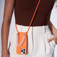 a woman wearing an orange cell phone case with white beads and a dog paw on it