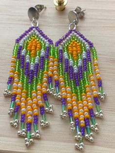 a pair of colorful beaded earrings sitting on top of a wooden table