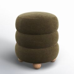 a round ottoman with three wooden legs on a white background, it is designed to be used as a stool or footstool