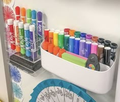 an organized desk with markers, pens and scissors on it in a white container next to a clock