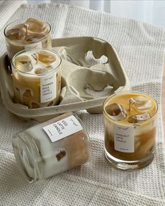 three jars filled with liquid sitting on top of a white table cloth next to an empty tray