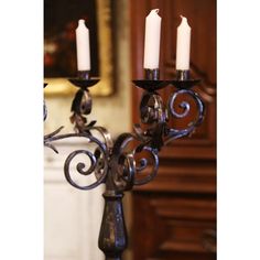 three candles are lit on an iron candelabra