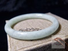 This 62mm inner diameter jade bangle bracelet features certified natural white jade, offering a timeless vintage style. Perfect as a meaningful gift for Christmas or New Year, it showcases the beauty of high-quality, authentic jade. Add a touch of elegance to any occasion with this exquisite piece of vintage jewelry, symbolizing luck and prosperity. Ideal for vintage jewelry lovers and those seeking a unique, thoughtful present for the holiday season. Size: 62mm Inner Diameter. The bangle is exquisitely crafted by skilled artisans, featuring intricate stone veins. This is a carefully selected piece just for you. NOTE: As it is made entirely from solid jadeite, please measure your wrist carefully before ordering. If you have any questions about choosing the right size, contact us through th Spiritual Jade Bangle For Gift, White Bangle For Gift, Jade Bangle Bracelet, Jade Bangle, White Jade, New Year Gift, Bracelet Vintage, Nouvel An, Jewelry Lover