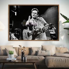 a black and white photo of a man playing the guitar in front of a couch