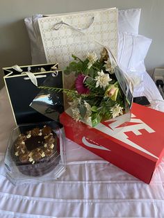 two boxes with flowers and a cake on a bed