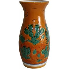 an orange and green vase with cactus designs on it's sides, against a white background