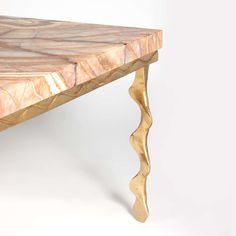 a marble top coffee table with gold leaf legs and an intricate design on the edge