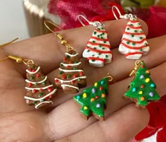 small christmas tree shaped earrings are on someone's hand