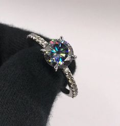 a diamond ring is sitting on top of a black sweater with white diamonds around it