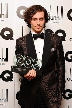 a man in a tuxedo holding an award for his role as the lead singer